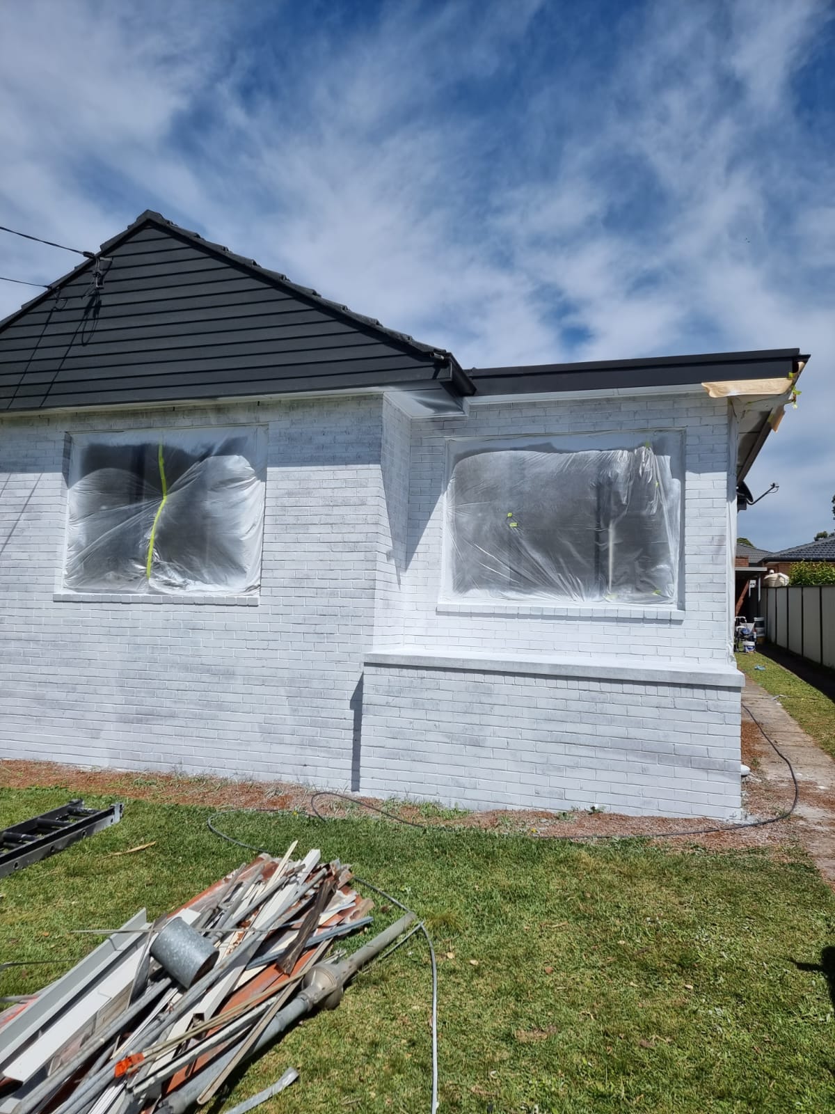 Freshly repainted white brick Sydney home exterior under blue sky