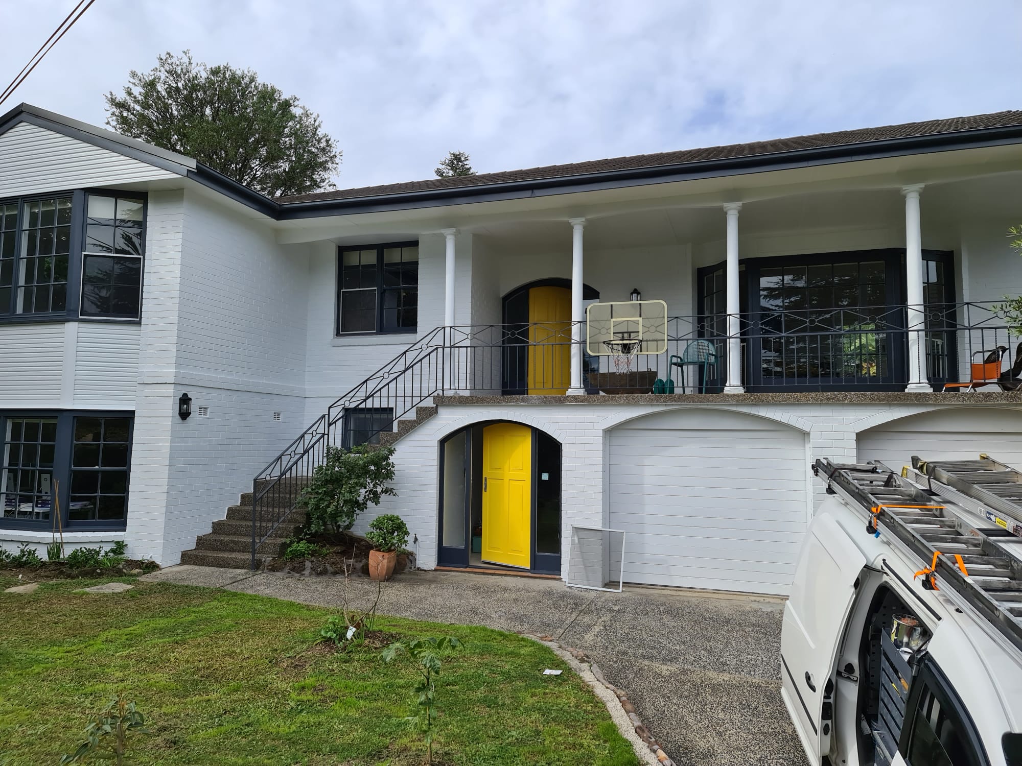 Freshly painted white home exterior with bold yellow feature doors in Sydney