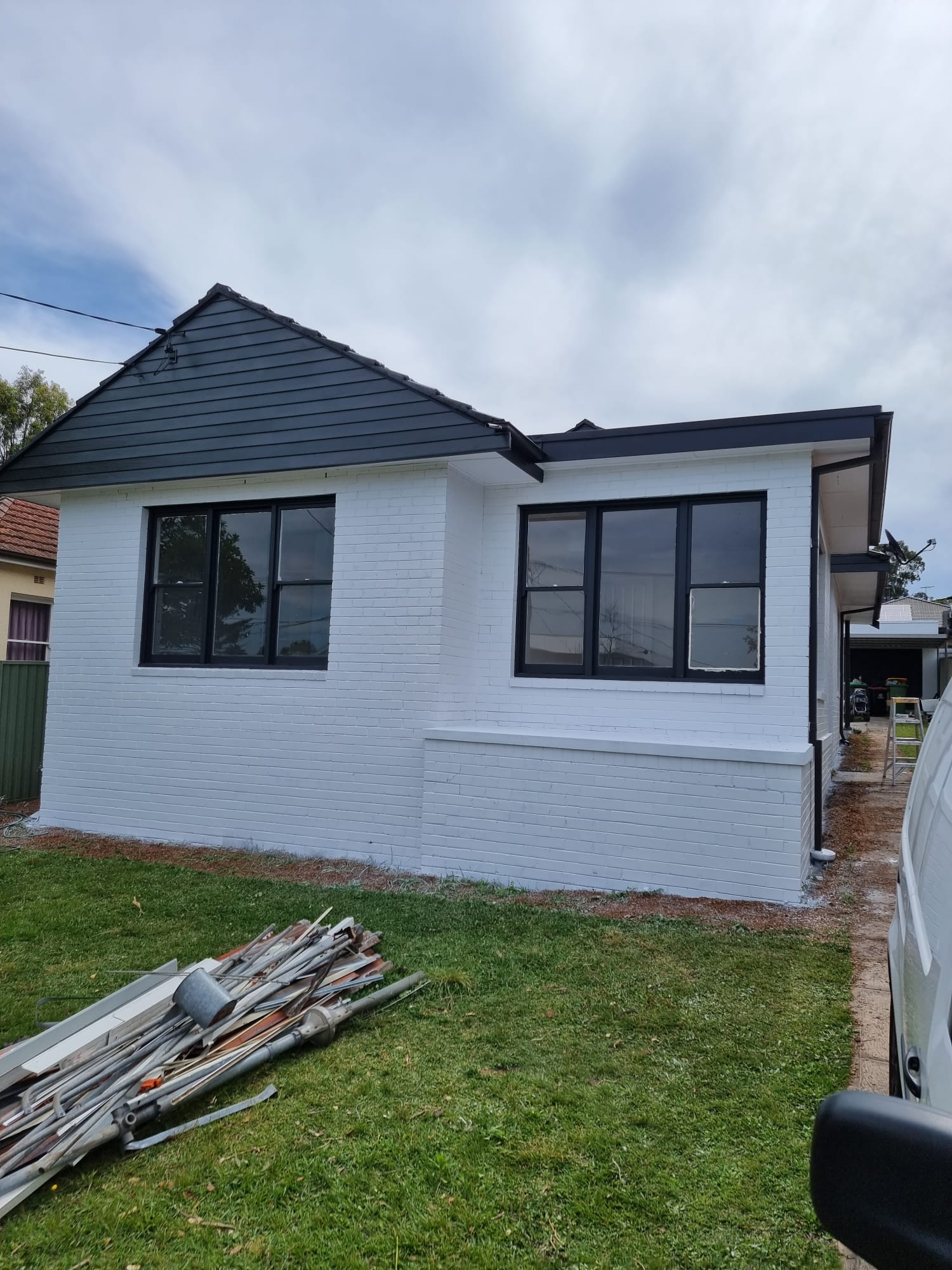 Weatherboard-look brick home freshly painted white with a charcoal gable roof