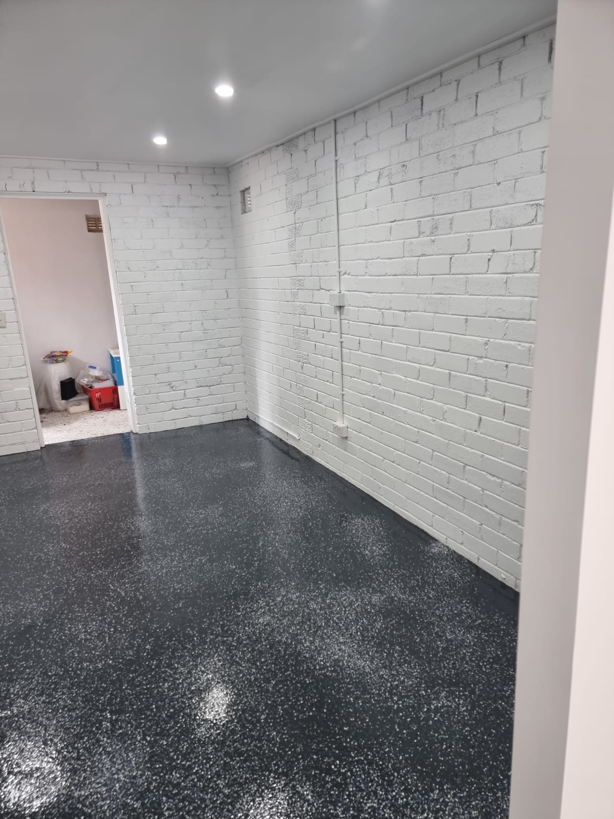 Garage converted to a living space with white-painted brick and a flake-coated floor