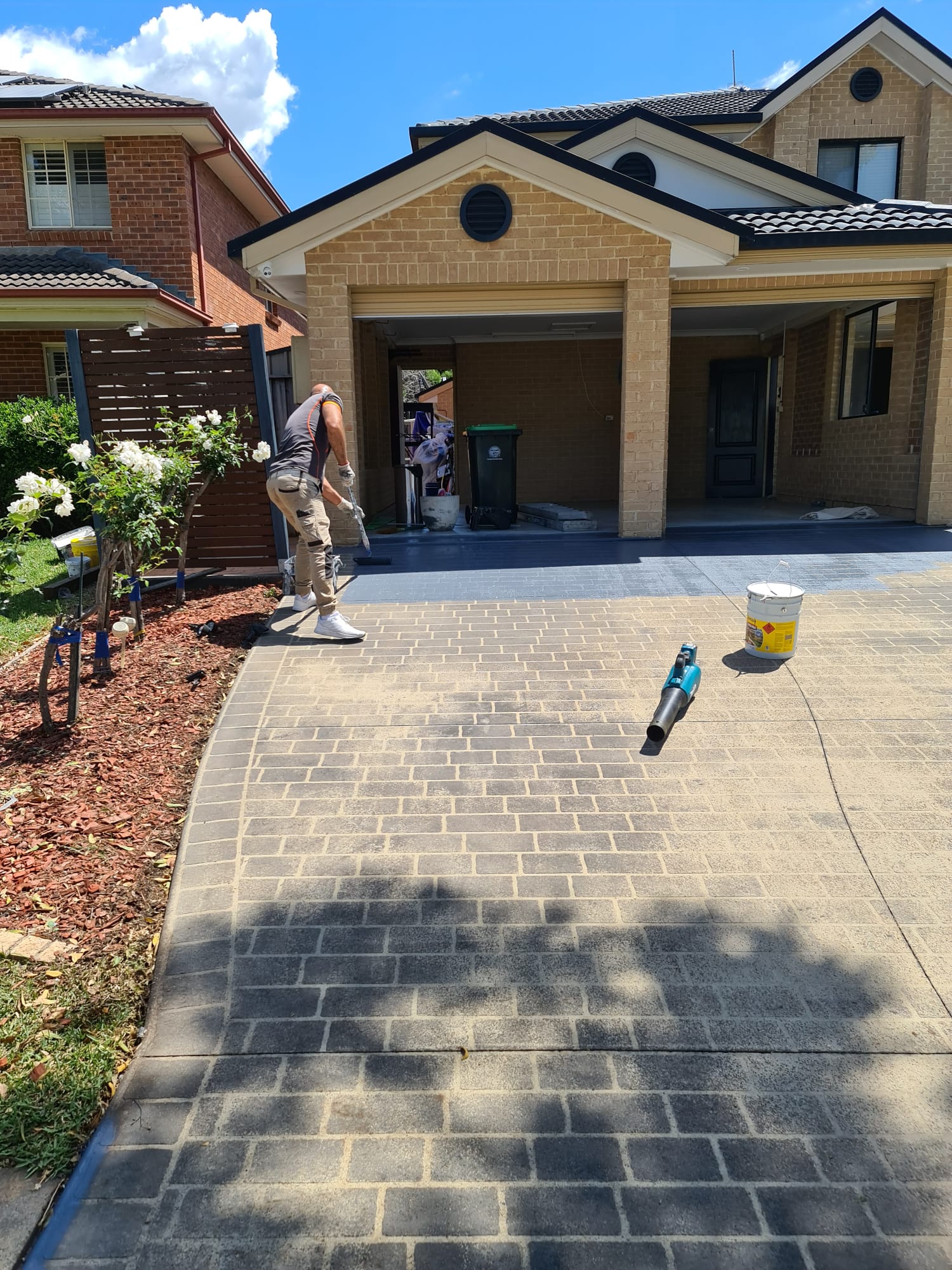 Maestro painter sealing a brick home driveway on a sunny Sydney day