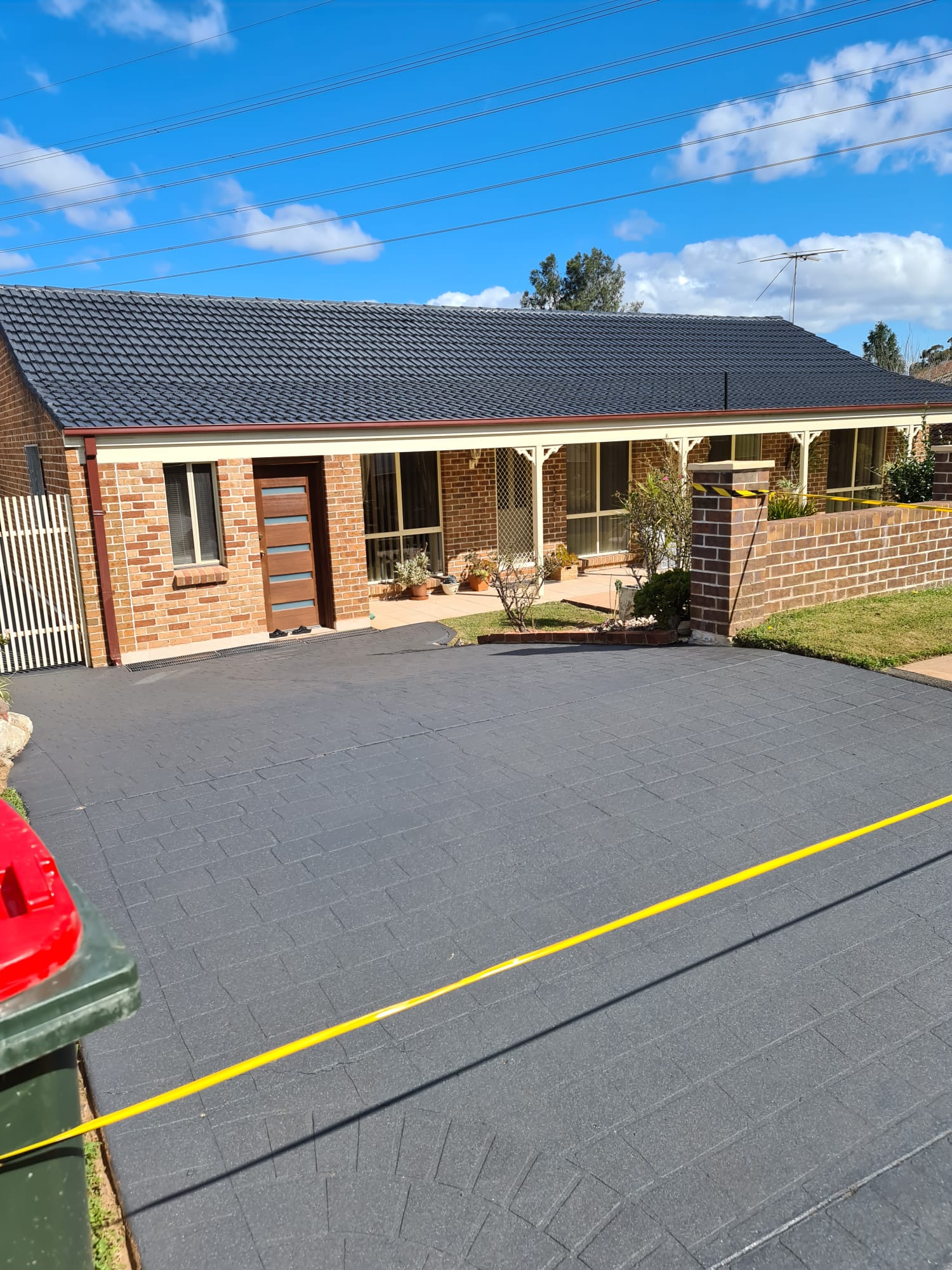 Brick home with a freshly coated charcoal roof and sealed driveway
