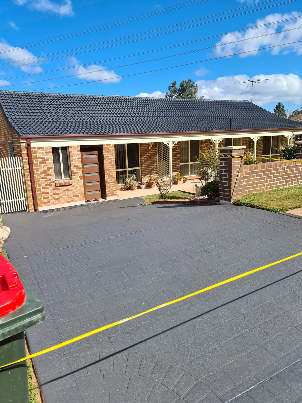 Single-storey brick home with a freshly sealed charcoal driveway