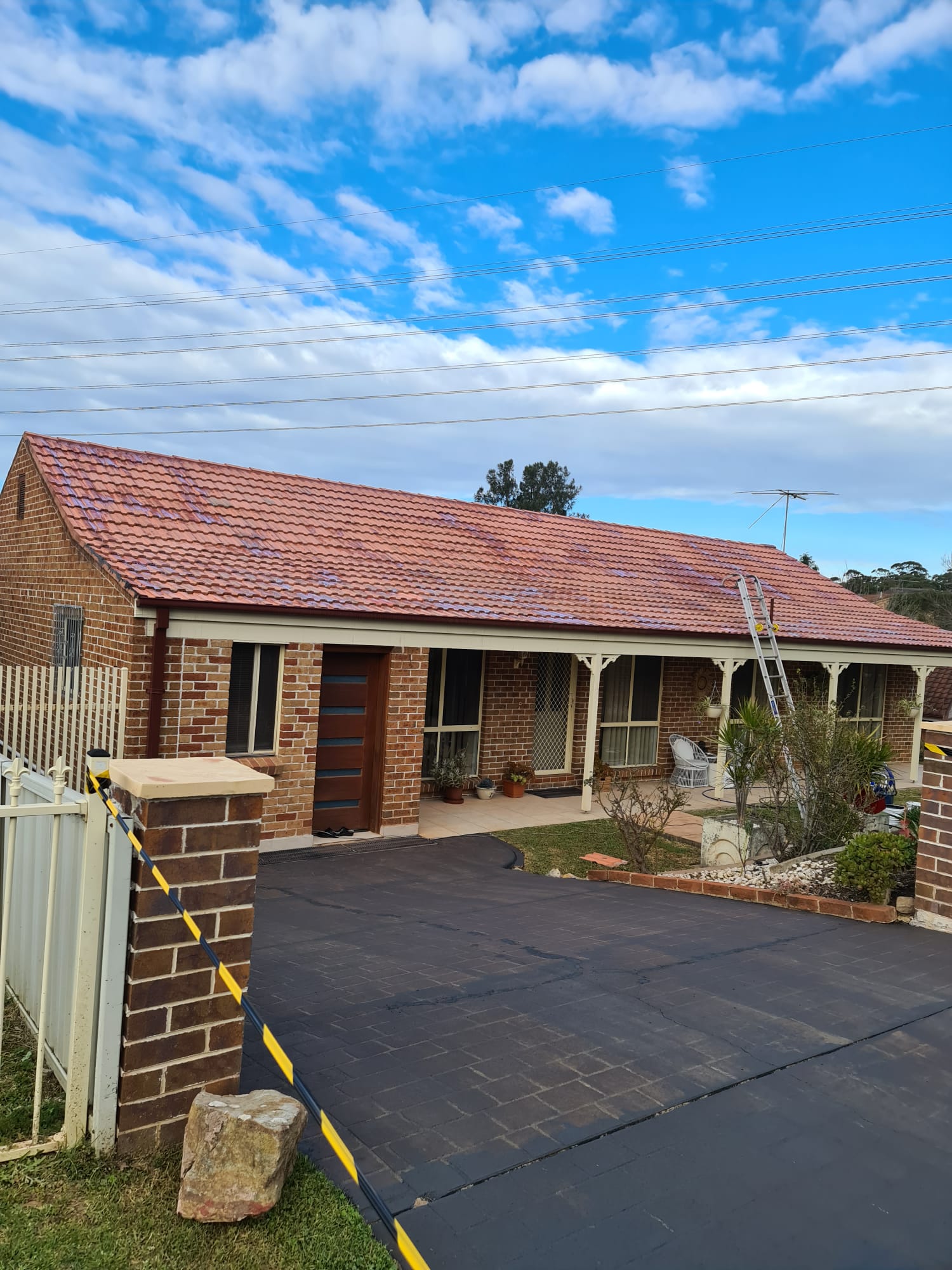 Brick Sydney home with a freshly painted red tiled roof and sealed driveway