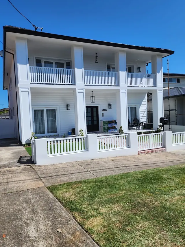 Two-storey Sydney home exterior repainted in crisp white with balcony and columns